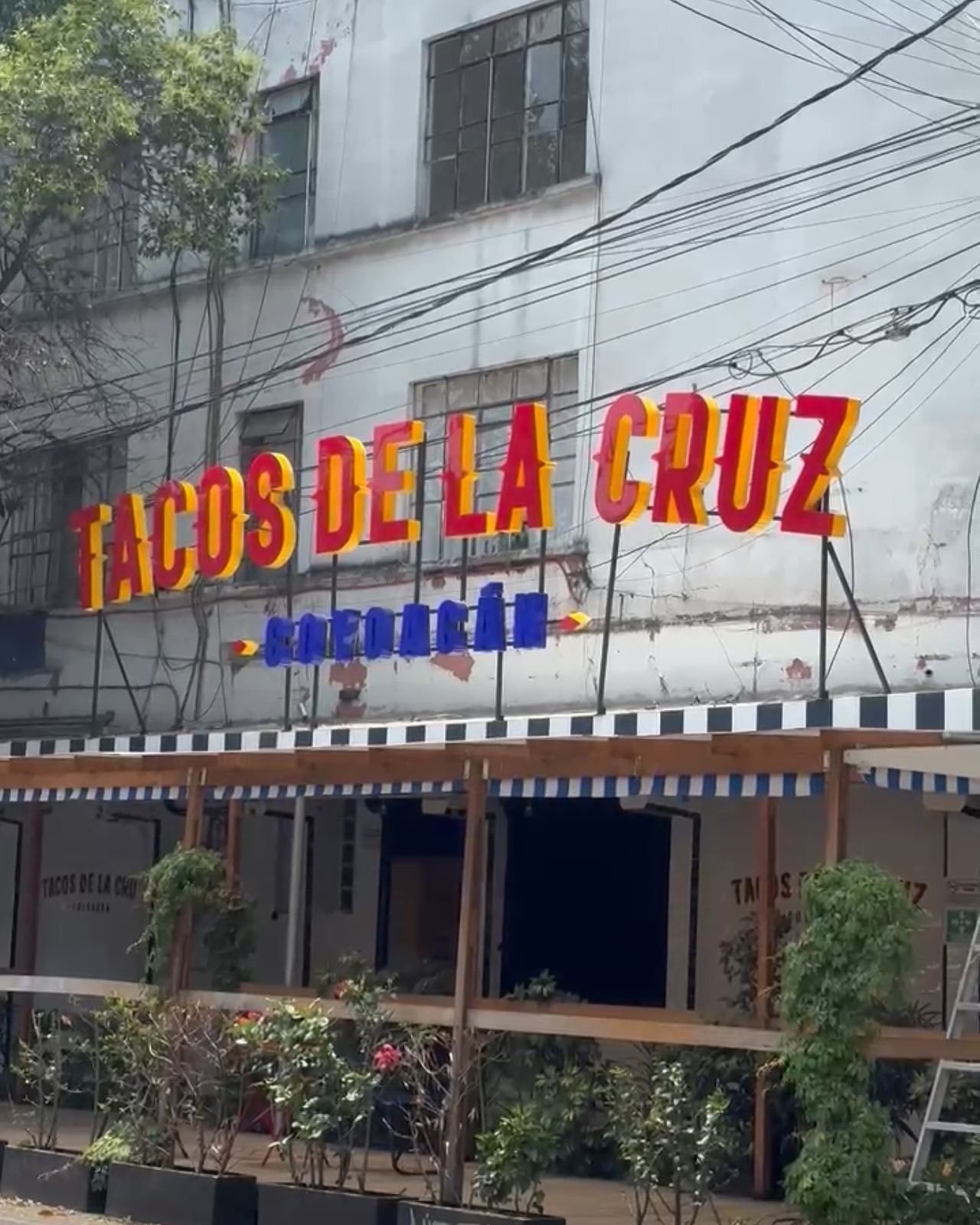 Fachada con letras rojas y amarillas de Tacos de la Cruz Coyoacán