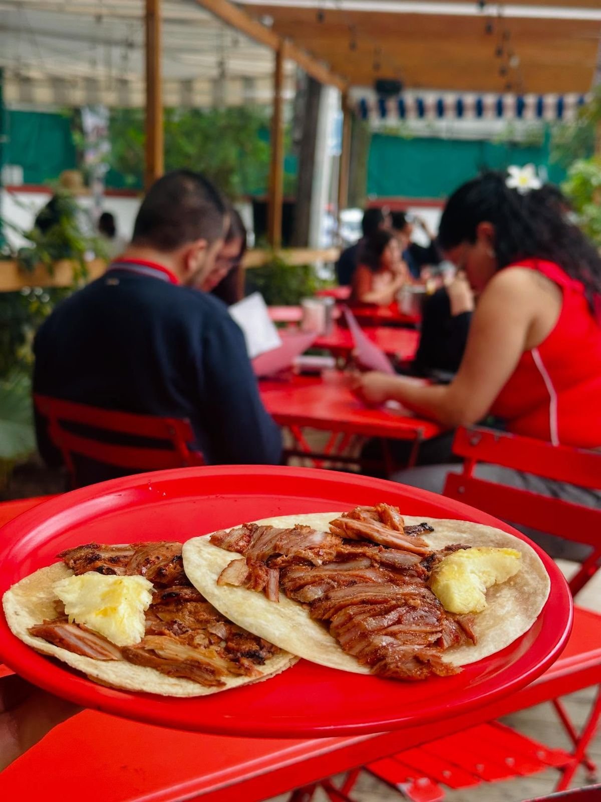 Dos tacos al pastor con piña en plato rojo