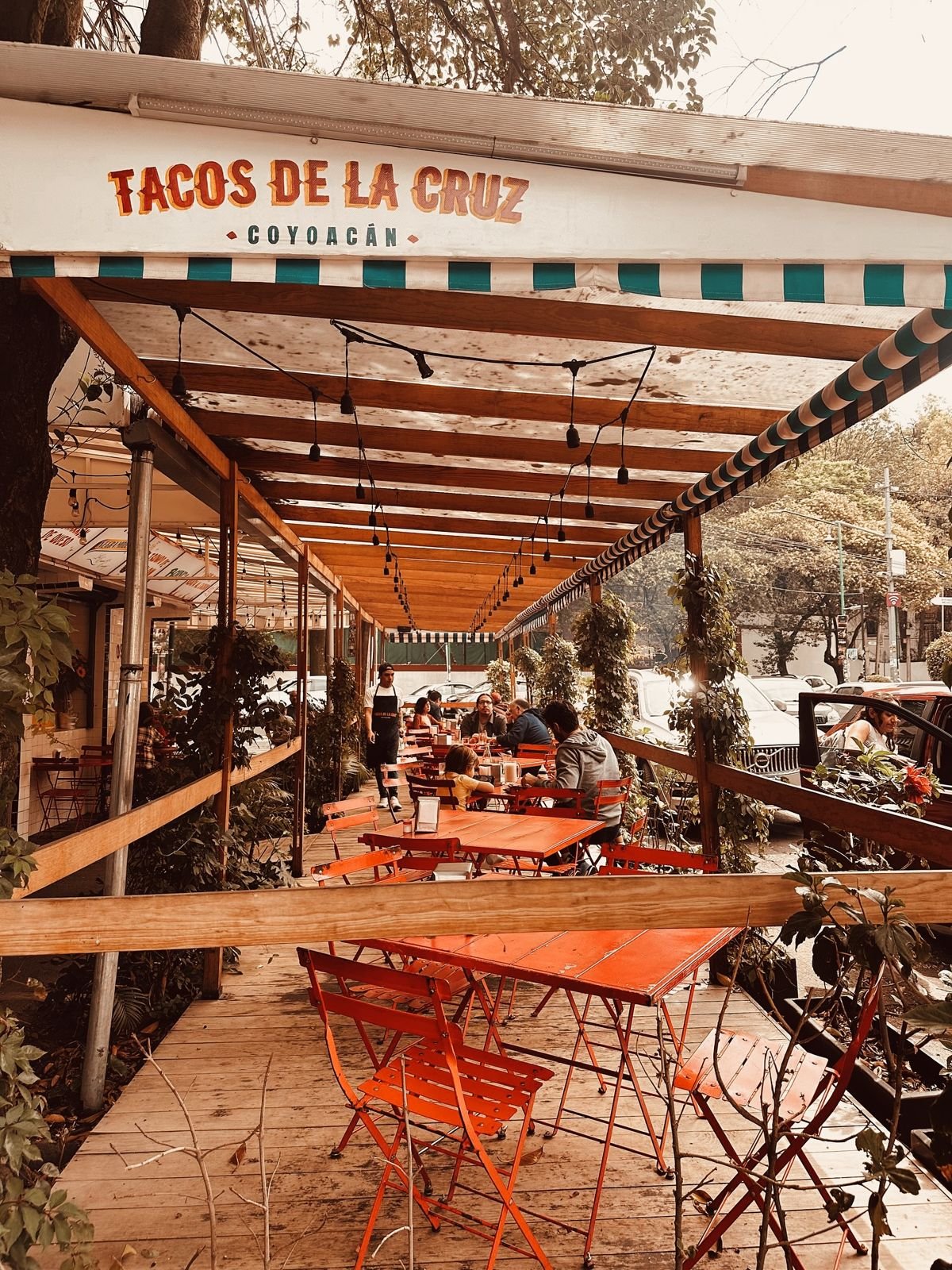 Terraza techada con mesas rojas y toldo a rayas