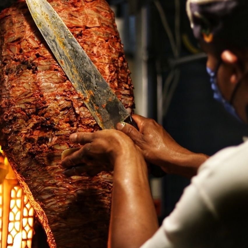 El taquero corta carne al pastor directo del trompo